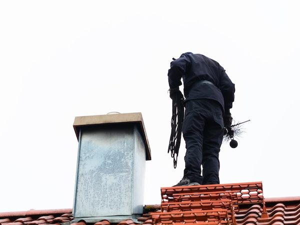 Chimney sweep standing on roof of home working